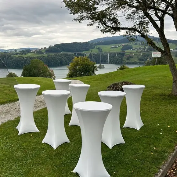 Mariage : tables hautes à housse blanche sur une pelouse au bord de l'eau