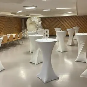 Soirée de gala : tables hautes à housse blanche et décoration de ballons dans une salle de fête
