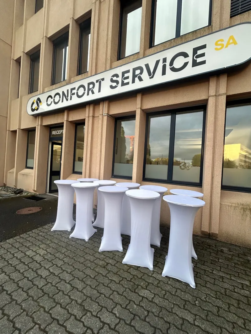 Anniversaire : tables hautes à housse blanche installées devant les bureaux d'une entreprise