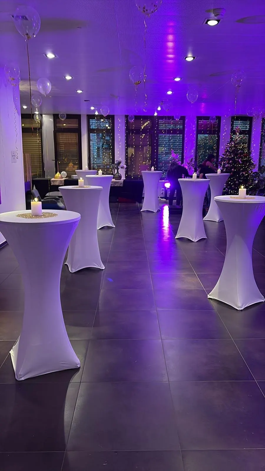 Tables hautes à housse noire décorées de fleurs lors d'un événement en Suisse romande